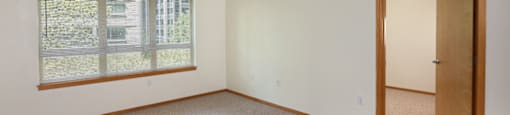 A room with a carpeted floor, a window with blinds, and a door.