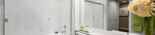 Spacious bathroom with oval soaking tub with glass enclosure, cultured marble vanity, glass shower, and built-in vanity at The Lanesborough Apartments in Houston.