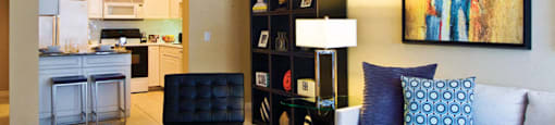 Spacious living room and bright kitchen with white cabinets at Tuscany Court Apartments in Houston.
