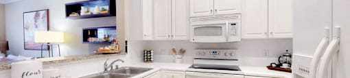 Bright kitchen with granite slab breakfast bar and white cabinets at Tuscany Court Apartments in Houston.