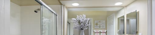 Luxury bathroom with tiled floors, oval soaking tub, built-in vanity, cultured marble vanity, glass shower and white cabinets in at TurtleCreek apartments in West Des Moines, Iowa
