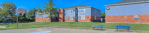 a basketball court with benches at Villas of Sorrento Apartments, Dallas, 75241 in front of two brick buildings