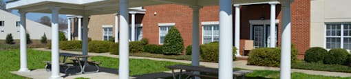 Outdoor grilling and entertaining area with covered picnic benches; charcoal grills