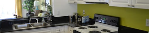 Kitchen with white cabinets, black granite countertops and an opening with a view through to the living room