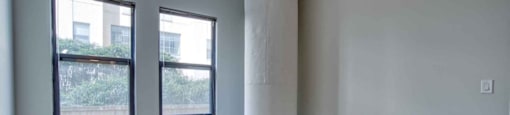 an empty room with a column and three windows