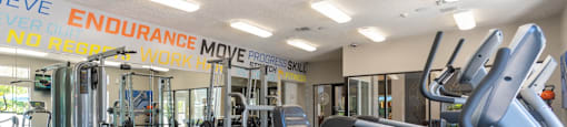 A gym with a variety of equipment including treadmills, weights, and exercise machines.