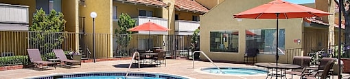 Sienna Apts Pool and Jacuzzi area with orange umbrellas covering sitting areas.