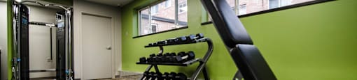a gym with weights and a chair in the corner of a room
