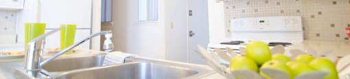a white kitchen with a sink and a bowl of fruit