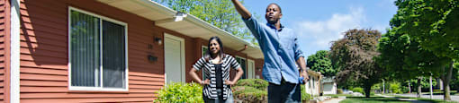 a man and woman standing in front of a house with a kite