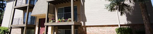 the exterior of an apartment building with balconies and a tree