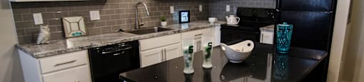 a kitchen with black countertops and white cabinets and a black refrigerator