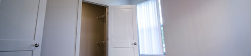 an empty room with a door to a closet and a window