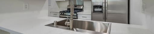 A modern kitchen with a stainless steel sink and white cabinets.