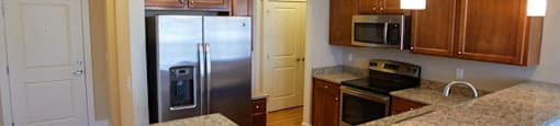 a kitchen with granite counter tops and a stainless steel refrigerator