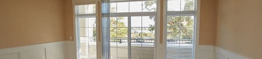 an empty living room with a ceiling fan and a balcony