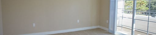 an empty living room with a ceiling fan and a sliding glass door