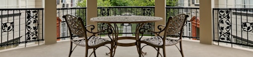 Van Nuys Apartments for Rent - Colonial Manor - Steel Decorative Table and Chairs Set, Black Steel Railing, and Brown Columns