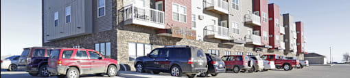 Apartment building with cars parked in front.