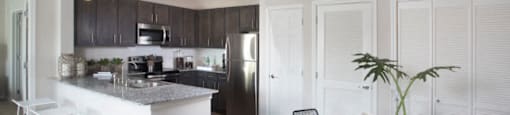 an open kitchen and dining area with a table and chairs and a refrigerator and microwave