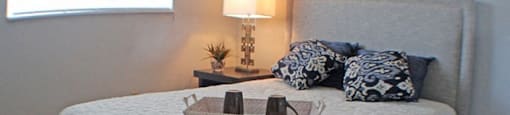 a bedroom with a bed, nightstand, and a window  at Valley York Apartments, Parma Heights, OH
