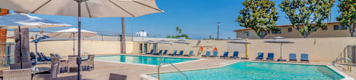 Pool area with lounge furniture and umbrellas at Serrano Apartments, California