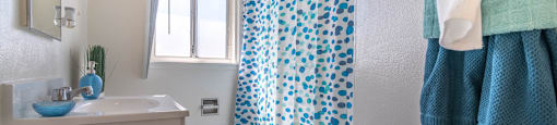 bathroom with colorful shower curtain over tub shower at Serrano Apartments, West Covina, 91790