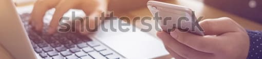 a man is using a laptop computer and a cell phone at the same time