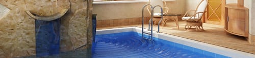 a swimming pool with a stone wall and a blue pool