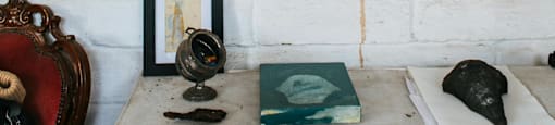 A white brick wall with a variety of objects including a globe, books, and framed pictures.