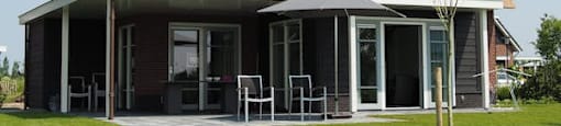 a house with a straw roof and a patio with chairs and an umbrella