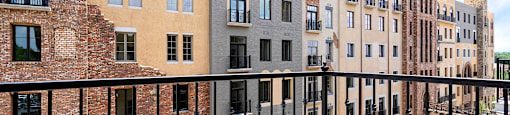 a balcony with a black railing and a view of a brick building