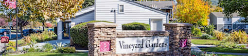 A sign that says Vineyard Gardens in front of a house.