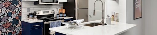 a kitchen with a white counter top and a stainless steel refrigerator