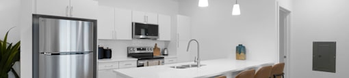 A modern kitchen with a white island and brown barstools.