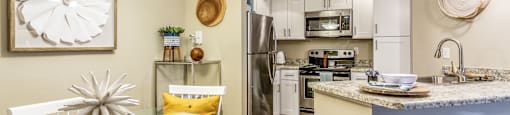 a dining area with a glass table and chairs and a kitchen with stainless steel appliances at Fusion Apartments, Orlando, FL 32818