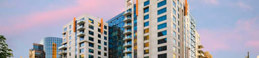 A modern multi-story building with a glass facade is situated on a street corner.