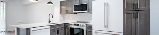 A modern kitchen with a white refrigerator, wooden floors, and dark brown cabinets.