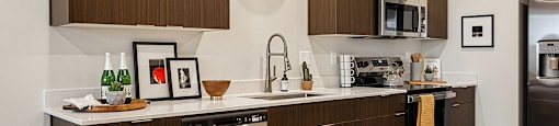 A modern kitchen with dark wood cabinets and stainless steel appliances.