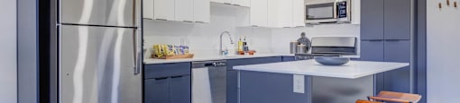 A modern kitchen with a large island and stainless steel appliances.