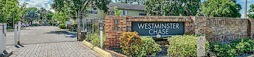 The image shows a brick wall with a sign at Westminster Chase Apartments, Apartments, Tampa, FL