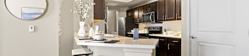 a kitchen with a bar and stools in a renovated apartment at Ridge at Thornton Station Apartments, Thornton, CO