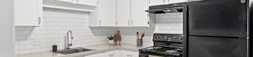 a kitchen with black appliances and white cabinets at Rosemont Square, Randolph, Massachusetts
