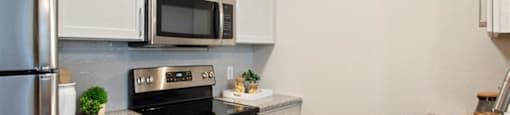 a kitchen with stainless steel appliances and white cabinets at Volare at the Woodlands, The Woodlands, TX