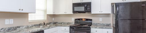 a kitchen with white cabinets and black appliances