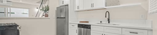 a white kitchen with white cabinets and stainless steel appliances