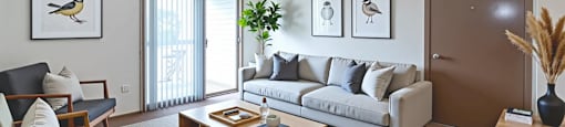 A living room with a sofa, a chair, a coffee table, and pictures on the wall.