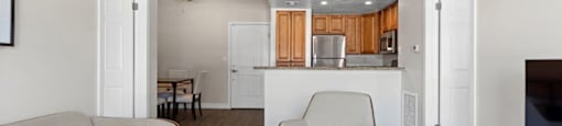 a living room and kitchen with a couch and a chair at Woodland Trio Apartments, North Hollywood