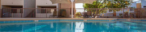 A swimming pool in front of a building with a sunny sky.