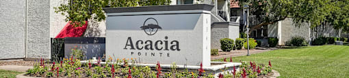 A sign that says Acacia Pointe in front of a building.